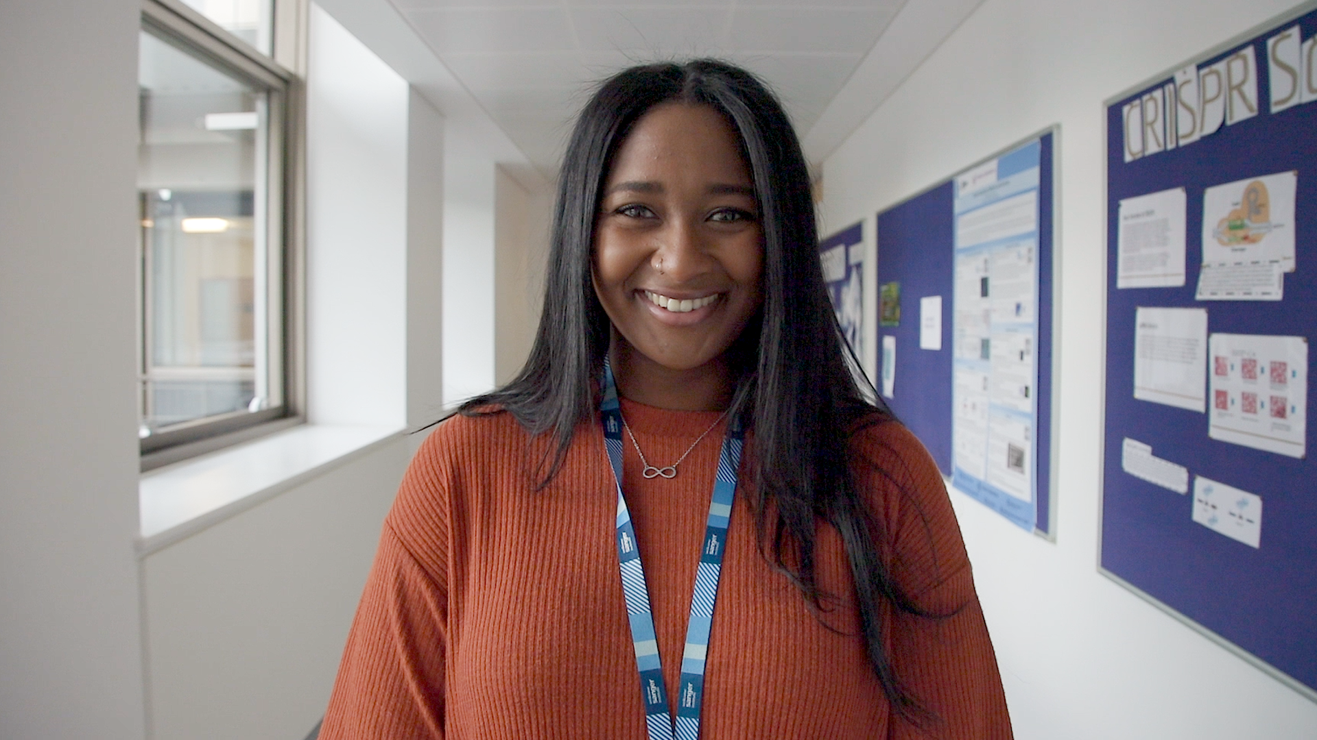 Picture of Jade smiling in one of the corridors in the Wellcome Sanger Institute.