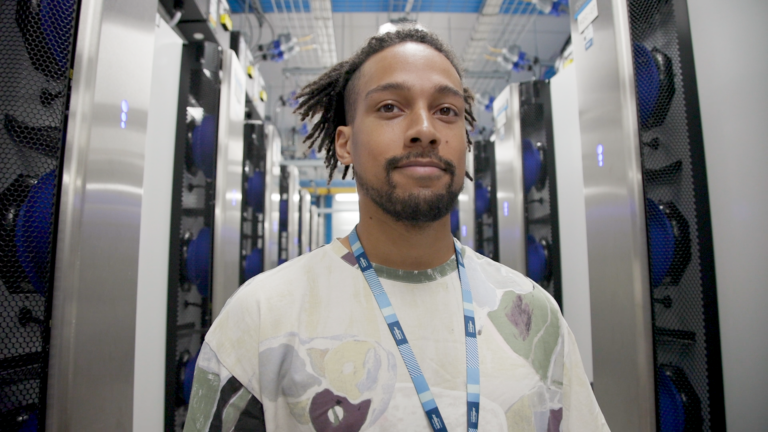 Picture of Tobi smiling, he is in a server room.