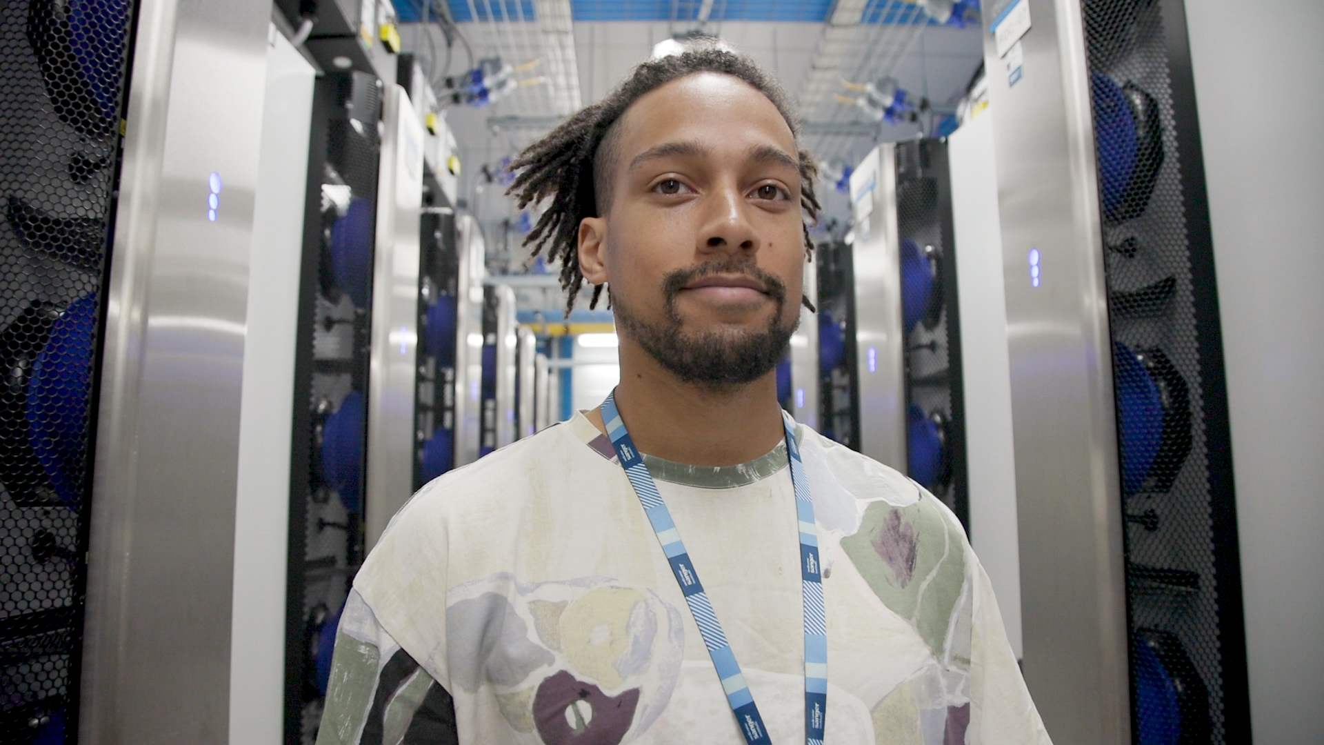 Picture of Tobi smiling, he is in a server room.