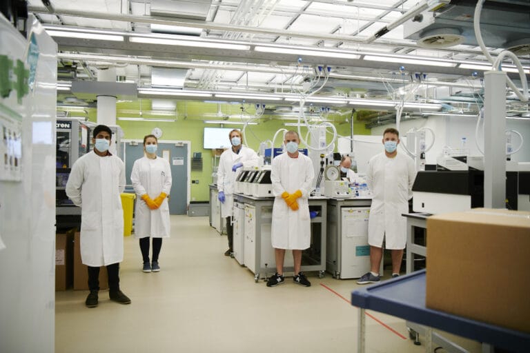 scientists in the lab wearing, masks, gloves and lab coats