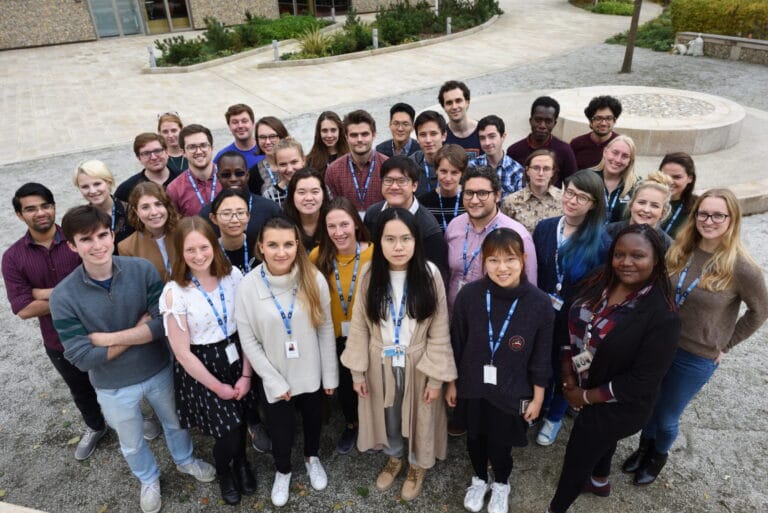 Picture of multiple colleagues at the Wellcome Sanger Institute, all smiling at the camera.
