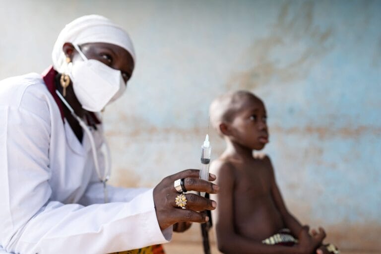 A medical professional preparing a vaccine for a child.