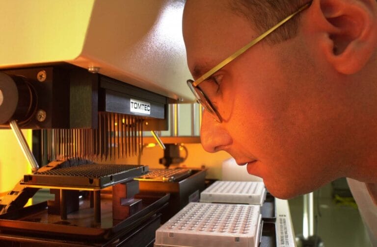 Sir Mike Stratton looking at a genetic instrument in the laboratory