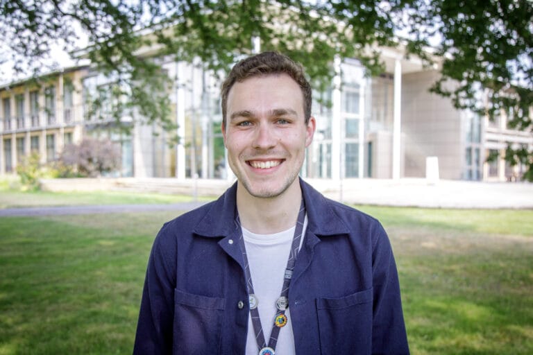 Picture of Sam smiling on the grounds of Wellcome Genome Campus.