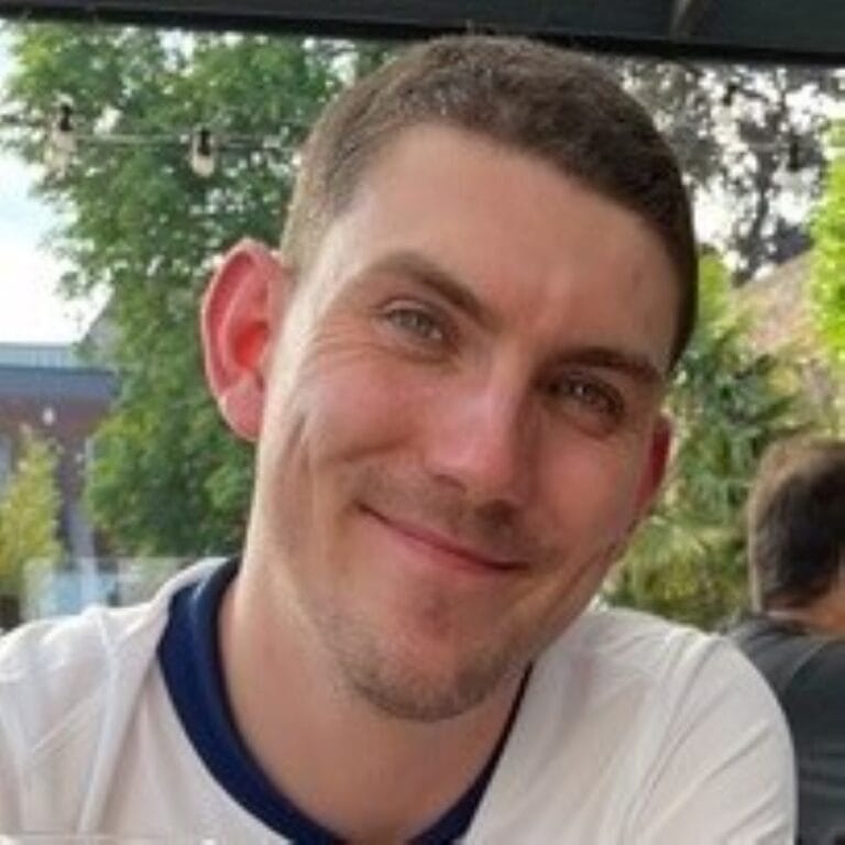 Image of Connor, a man smiling, in a white t-shirt whilst sat outside. Image of Connor, a man smiling, in a white t-shirt whilst sat outside.