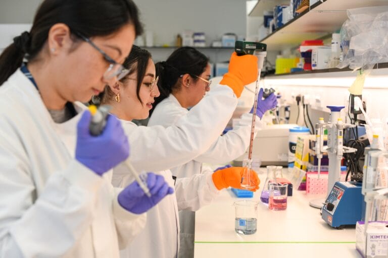 Three female scientists in a biology laboratory conducting experiments
